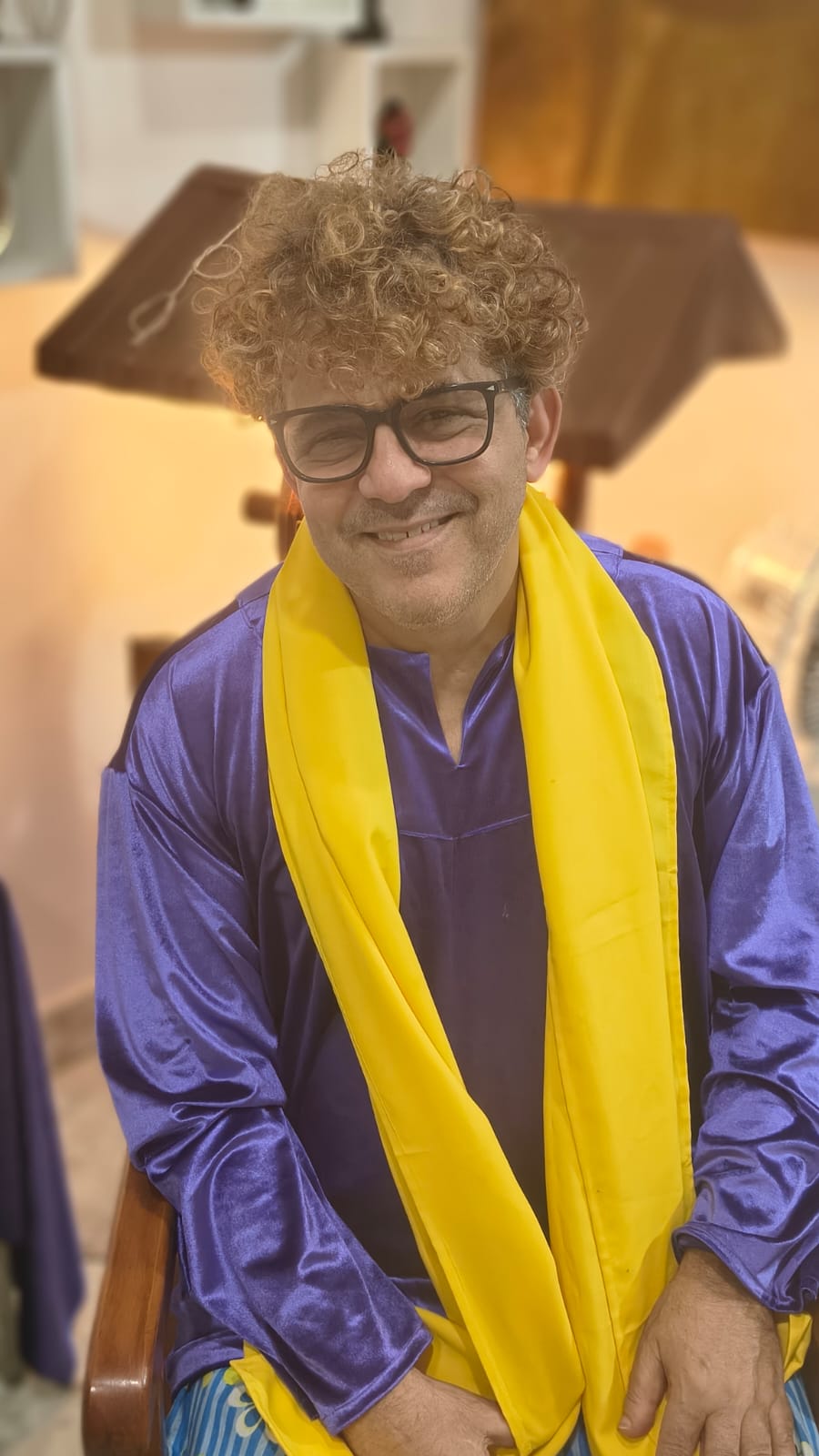 Pai Vinny de Logun sorrindo, vestido de roxo e amarelo